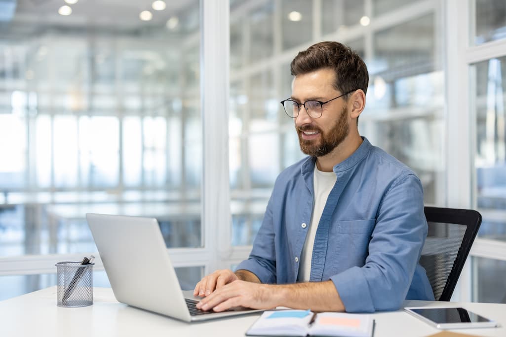 professional man wearing glasses working on salesforce on his laptop